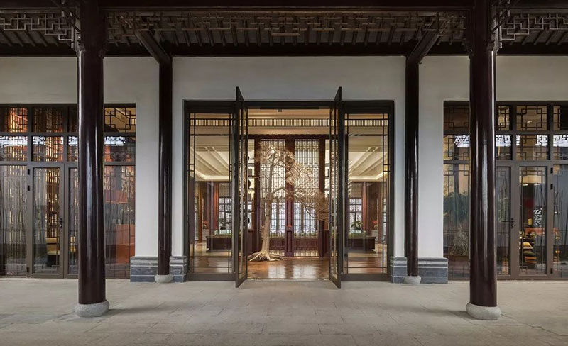 薰习于中国传统文化中的生活方式无奈渐远，携带一颗虔敬之心将其浓缩在这一方现代屋檐下的生活空间中，这是一个为现代人打造的古典雅韵空间，回归妙法自然、天人合一的生活。前厅设计延续了建筑的形制，衍脉传统中式的神韵，整体空间大气典重，沉着雅致的棕色和木制架构，唤醒了人们对传统的印象记忆，屋檐的镂刻花纹与窗棂上的设计互相呼应，造型古朴典雅。以传统宅门的型制延伸而出的镂空屏风，简洁而富有传